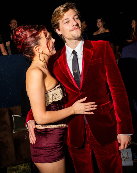 Millie Bobby Brown in a burgundy corset and shorts with Jake Bongiovi in a red velvet suit
